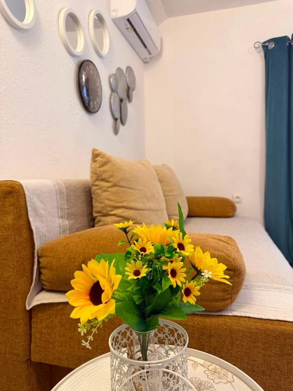 a vase with yellow flowers on a table in a living room at Apartmani Klarić in Zadar