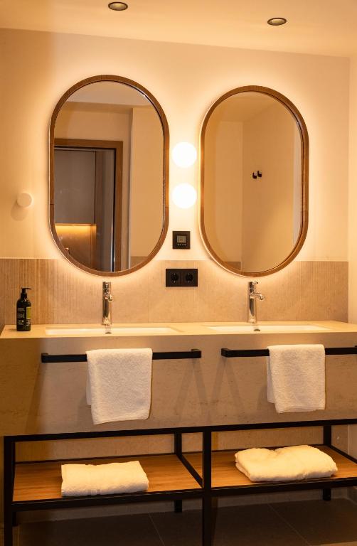 two mirrors above a sink in a bathroom at Garden Hotel Reinhart in Prien am Chiemsee