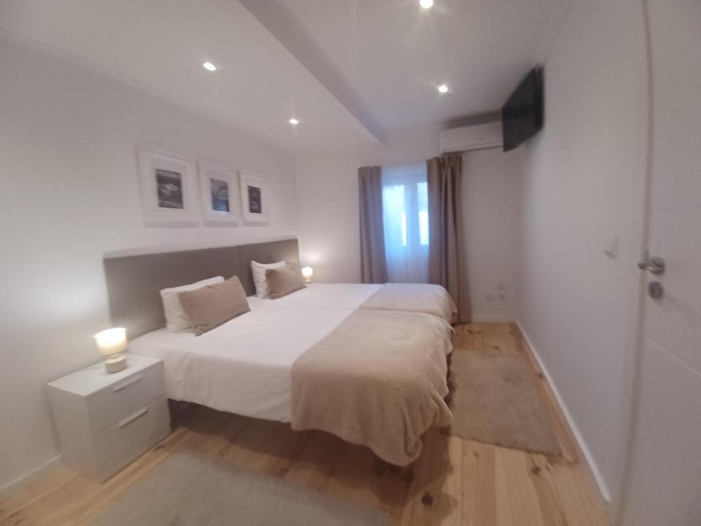 a white bedroom with a large bed and a window at Flor do Padrão in Elvas