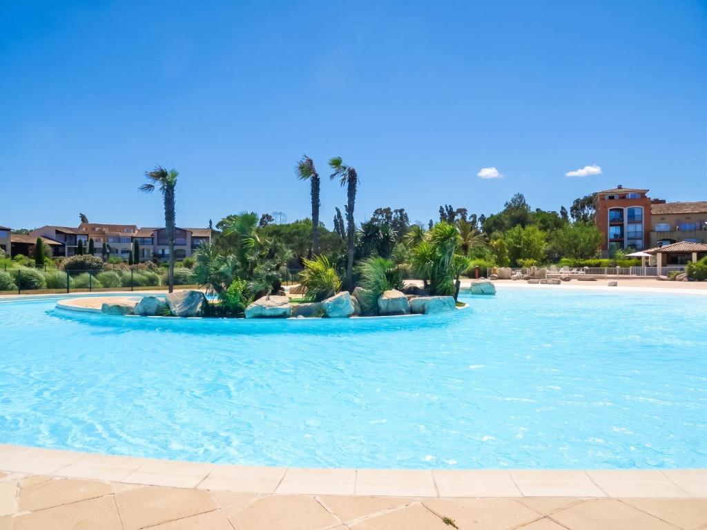 a pool at a resort with palm trees and rocks at Appartement convivial à Gassin 37 m² avec vue sur la mer in Gassin