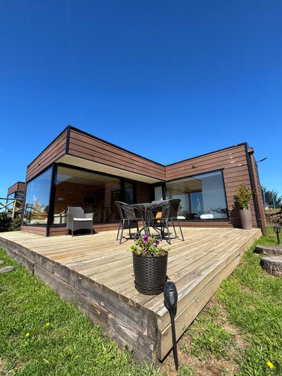 a wooden deck with a table and chairs on it at Cabañas Vista Volcanes del Sur in Llanquihue