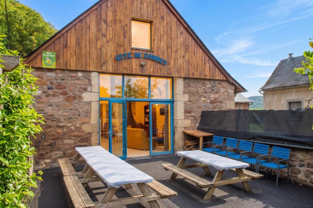 a building with two picnic tables in front of it at Grande maison conviviale à Saint-Côme-d'Olt avec jardin et cheminée in Saint-Côme-dʼOlt