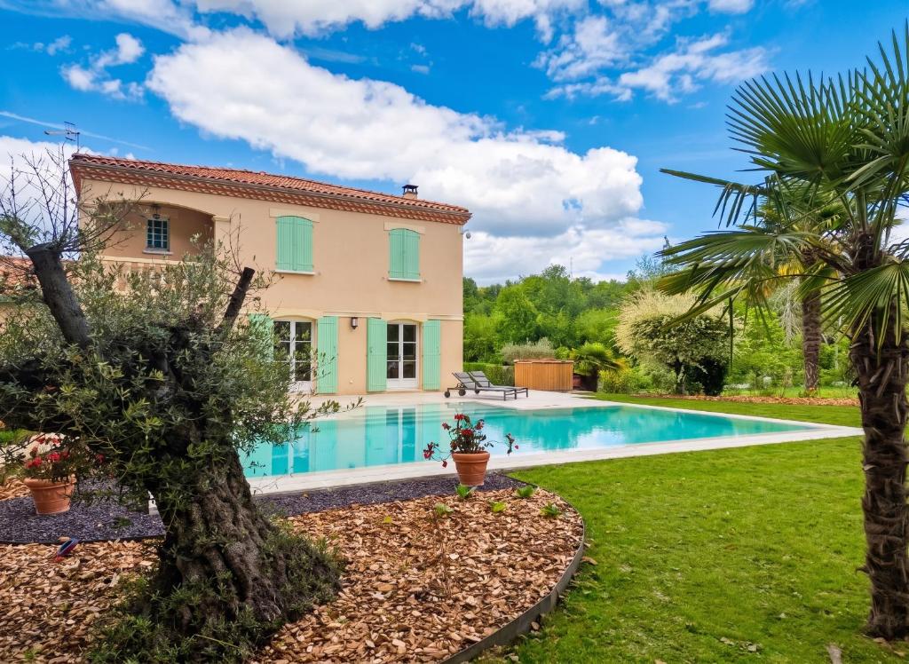 a villa with a swimming pool and palm trees at Villa de charme à Ribérac avec piscine privée in Ribérac