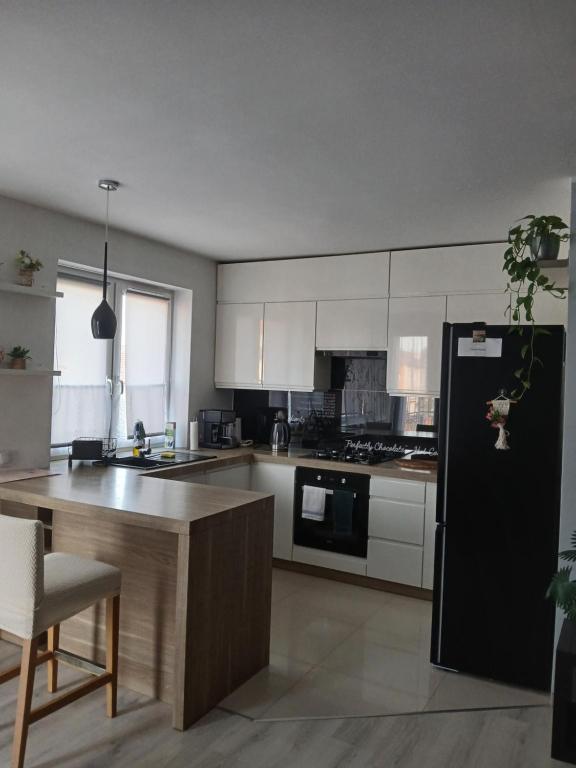 a kitchen with white cabinets and a black refrigerator at Duży Apartament 75m2 in Wągrowiec