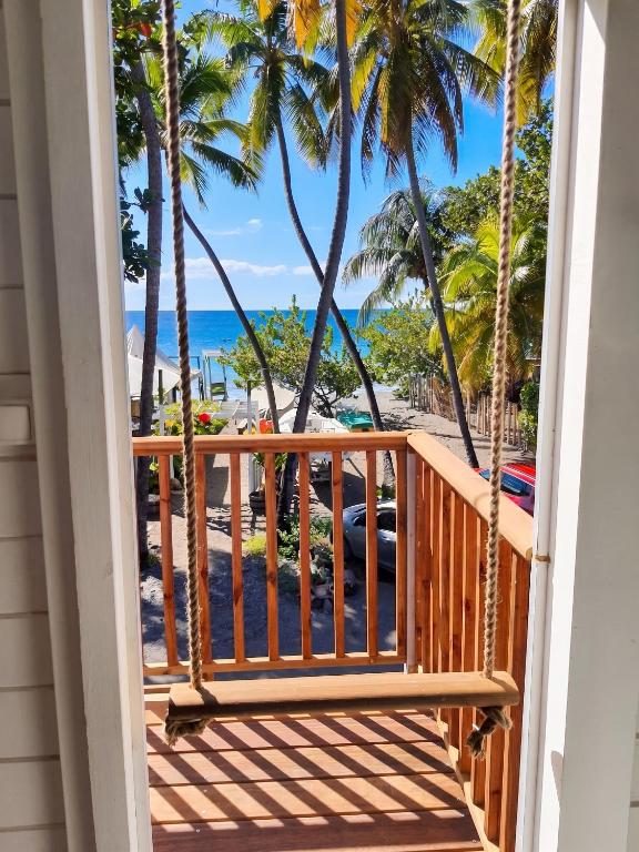 a porch with a view of the beach and palm trees at Appartement cosy au Carbet avec balcon et vue sur mer - 70 m² in Le Carbet
