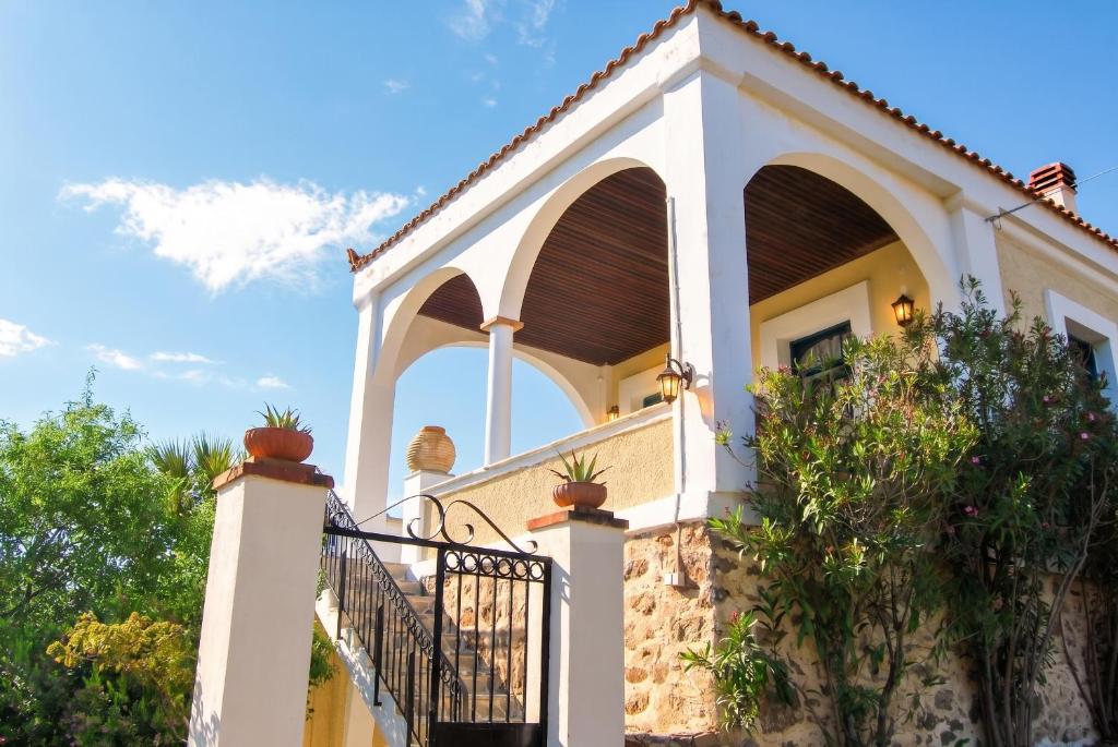a house with a balcony with potted plants on it at Picturesque Villa in Limnos + Enclosed Garden + Sea View in Lemnos