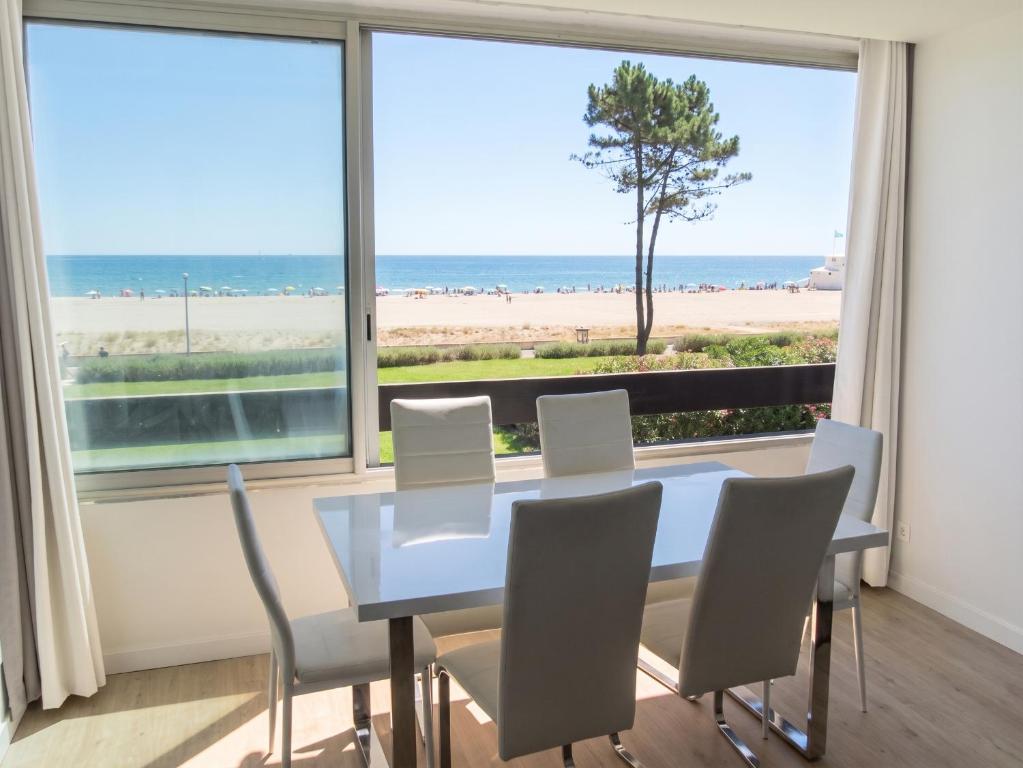 a dining room with a table and chairs and a view of the beach at Appartement lumineux à Saint-Cyprien 45 m² vue mer in Saint-Cyprien