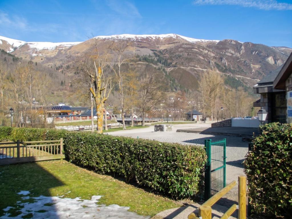 a building with a fence and mountains in the background at Appartement accueillant Saint-Lary-Soulan 45 m² Piscine partagée in Saint-Lary-Soulan