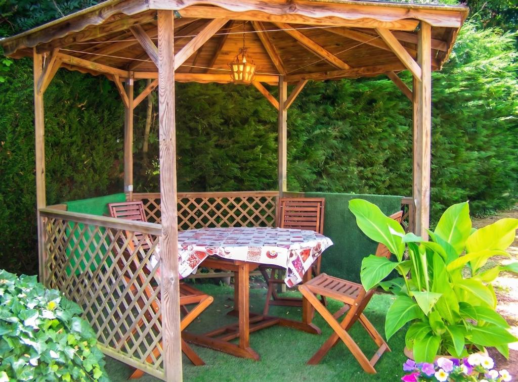 a table and chairs under a wooden gazebo at Maison accueillante à La Chapelle-aux-Choux avec jardin spacieux 70 m² in La Chapelle-aux-Choux