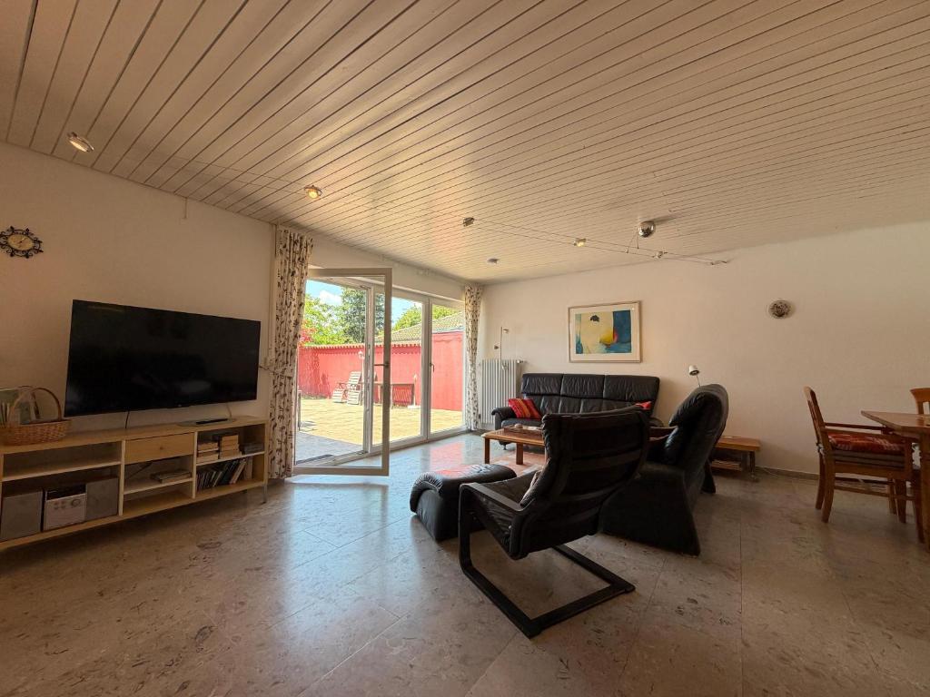 a living room with a flat screen tv and chairs at Casa Constantinus in Unteruhldingen