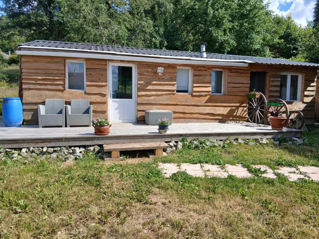 a log cabin with two chairs and a porch at Le Gite des 4 Voies in Bellefosse