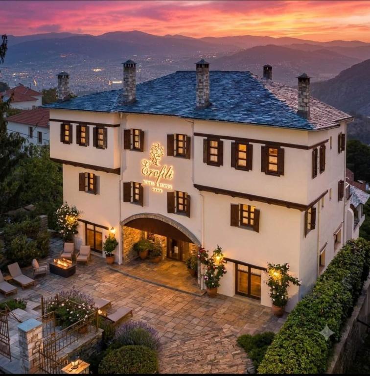 a large white building with a sunset in the background at Erofili Hotel & Suites in Portaria