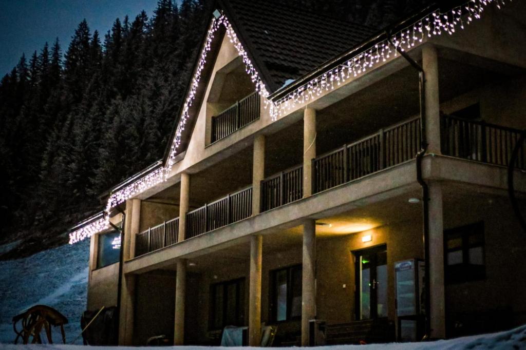 a building with lights on it in the snow at Casa Roua Munților in Dămuc