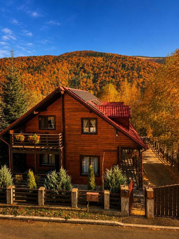 a wooden house with autumn foliage in the background at Old Mark's House Sinaia in Sinaia