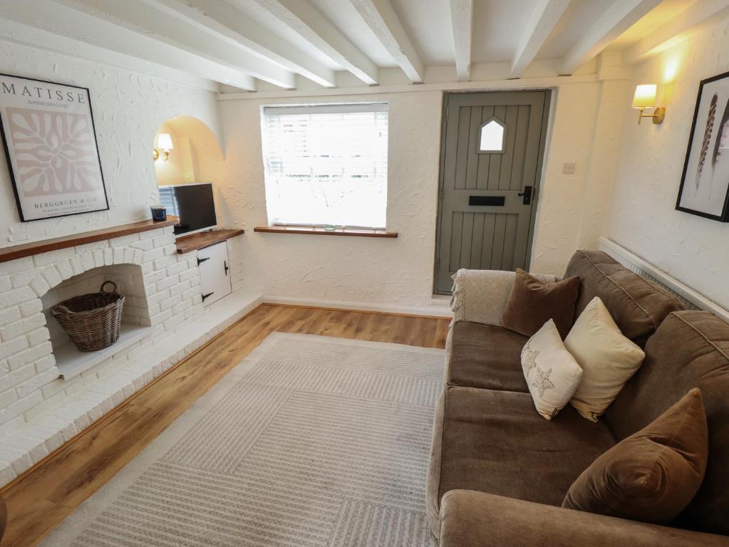 a living room with a couch and a fireplace at Pax Cottage in Beccles