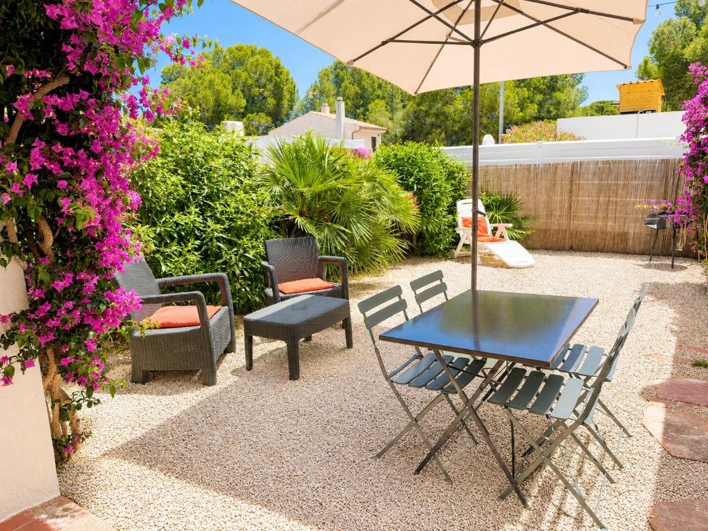 a patio with a table and chairs and an umbrella at Les cases del vent I in L'Ametlla de Mar