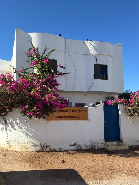 a white building with pink flowers on a wall at Lighthouse Residence in Dahab