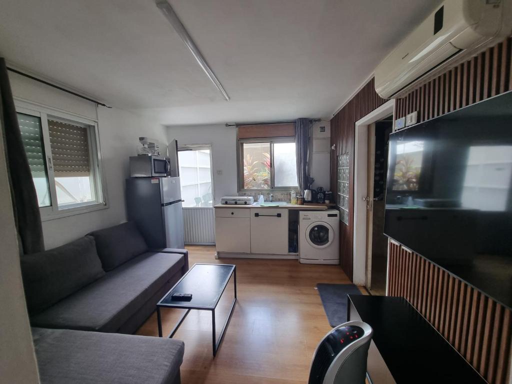 a living room with a couch and a kitchen at OSHER Simple house in Nahariyya
