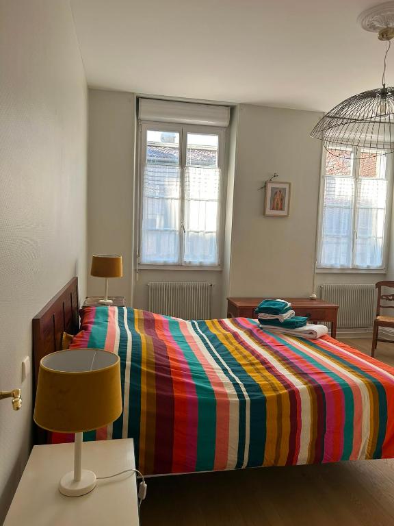 a bedroom with a bed with a colorful striped comforter at Agen centre in Agen