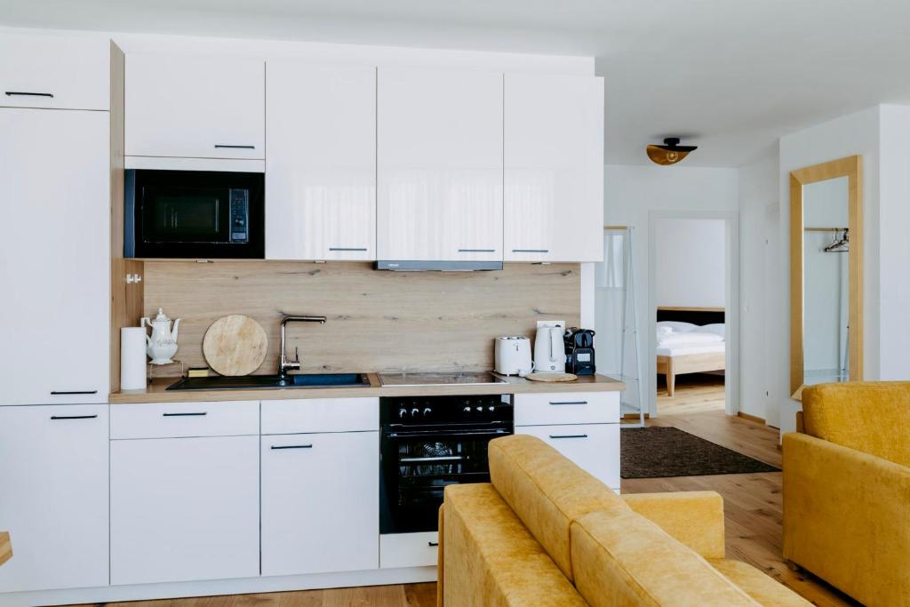 a kitchen with white cabinets and a couch at Beach SUN and FUN Penthouse in Podersdorf am See