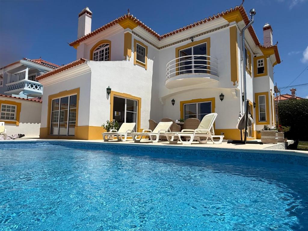 a villa with a swimming pool in front of a house at Villa Ericeira in Ericeira