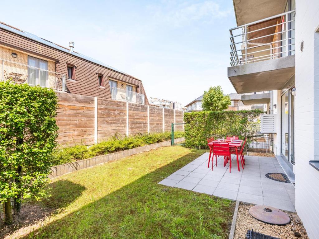 a patio with a red table and chairs in a yard at Beth gelijkvloers in Sint-Idesbald