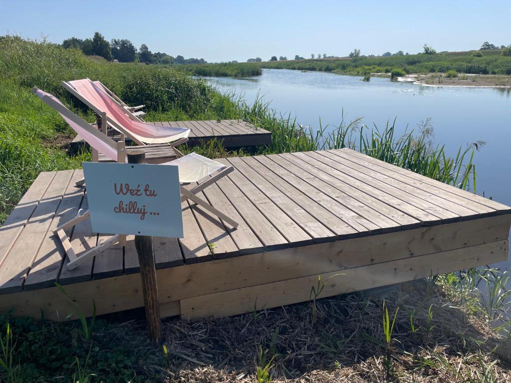 a wooden dock with two chairs and a sign on it at Weź Wyjdź - Podlaski Glamping in Łazy