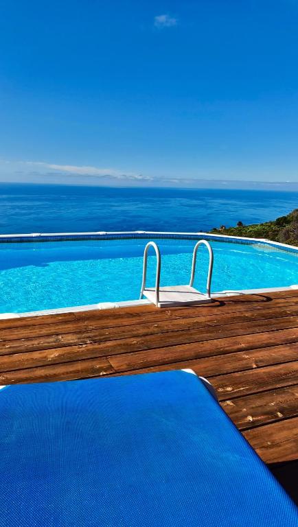 a wooden deck with a pool with the ocean in the background at Villa Las Flores - Piscina privada - Private pool - by Rural La Palma in Tijarafe