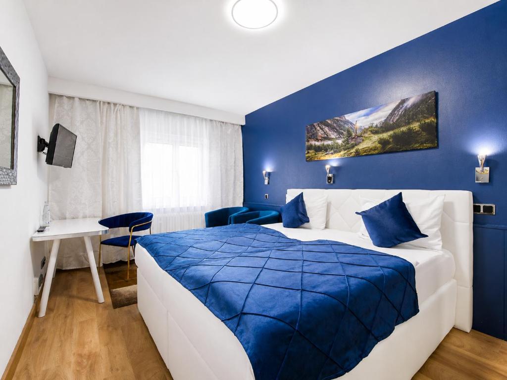 ein blau-weißes Schlafzimmer mit Bett und Schreibtisch in der Unterkunft Hotel Rivoli Charme in München