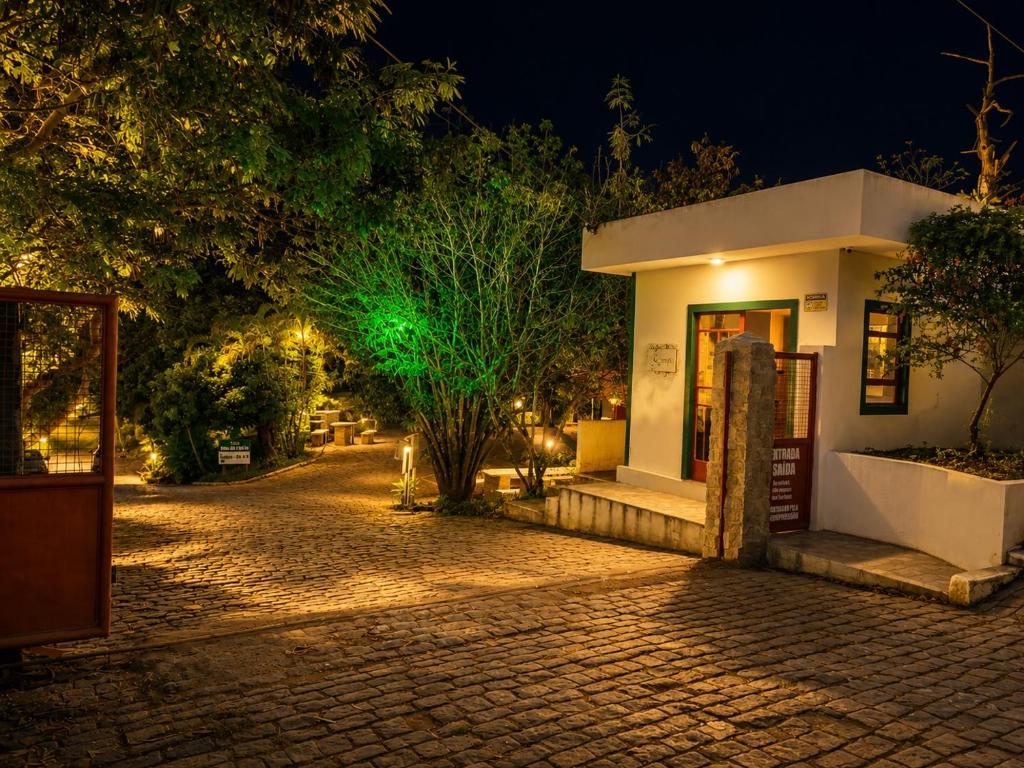 a small building with a green light in the night at Pousada Flat Royal Suíte com varanda e rede in Itapecerica