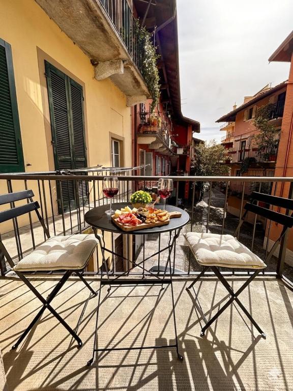 a table with food and wine glasses on a balcony at Casa Renoir appartamento a due passi dal lago in Verbania