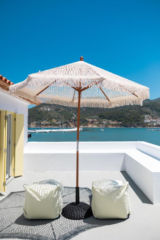 an umbrella sitting on a patio with two chairs at Nama Suites in Skopelos Town