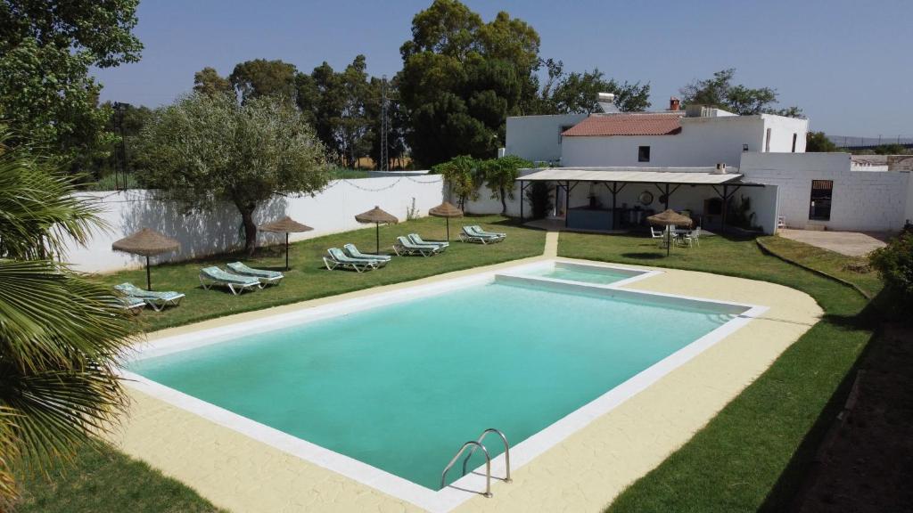 a swimming pool in a yard with chairs and a house at Casa Rural La Vega in Antequera