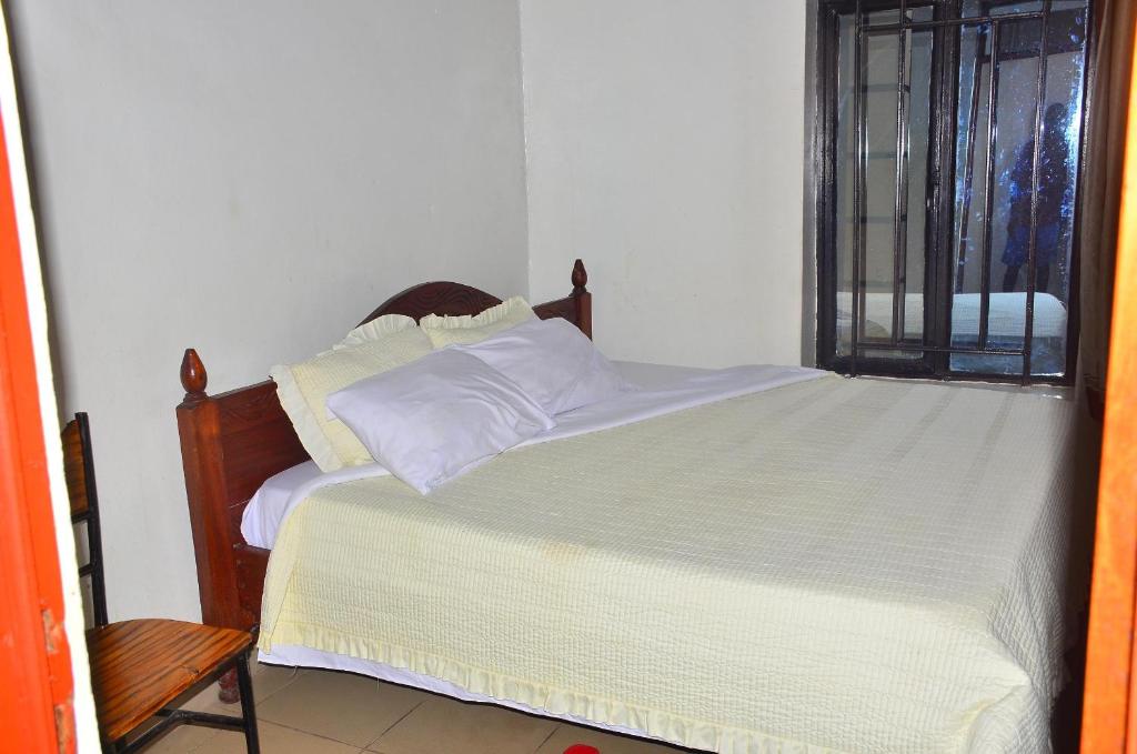a bedroom with a bed with white sheets and a window at Brabus Appartment Motel in Rubavu