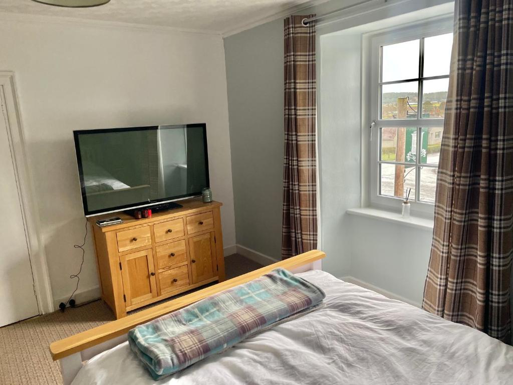 a bedroom with a television on a dresser with a bed at The Bognie Inn in Huntly