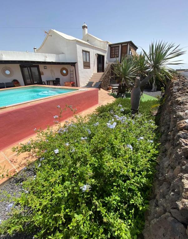 a house with a swimming pool and a wall at Guest House Ysabela Suite Privada y Habitaciones con Baño Compartido in Tías
