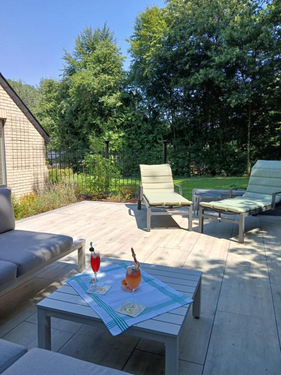 a patio with two chairs and a table with drinks on it at Le Loft du Renard, gîte cosy au coeur de la nature boisée à Namur Wépion, une parenthèse douce dans la vallée mosane in Namur