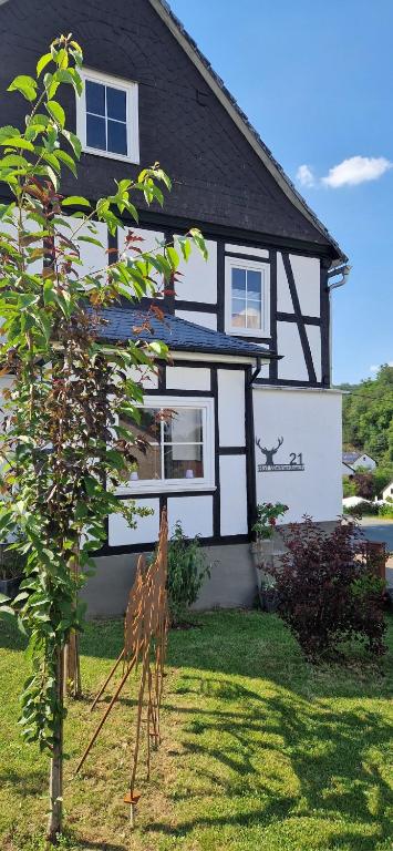 a black and white house with a tree in front of it at LandHaus Hof Wehlenbach in Hallenberg