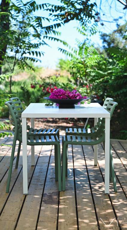 a table with a bowl of flowers and two chairs at l'Alzelle Plage in Biguglia
