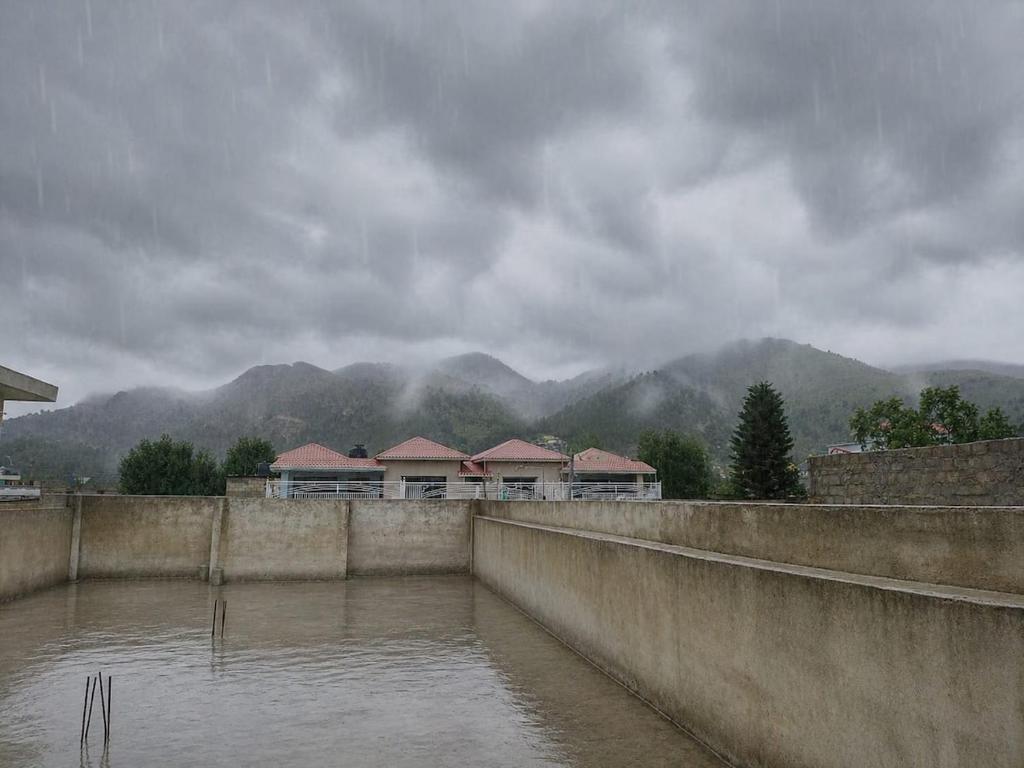 a group of houses in front of a body of water at Spacious 2 Bed Room Home Attached Baths, Lounge & Kitchen in Abbottabad