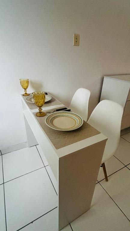 a white table with a plate and two chairs at Golden Stay Suites in Jacareí