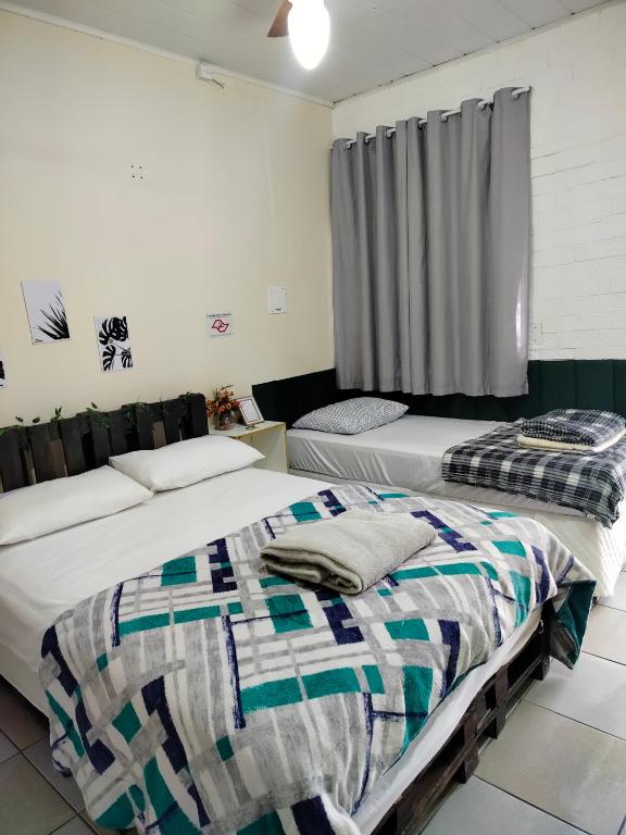 a bedroom with two beds and a window at Pernoitar in São José