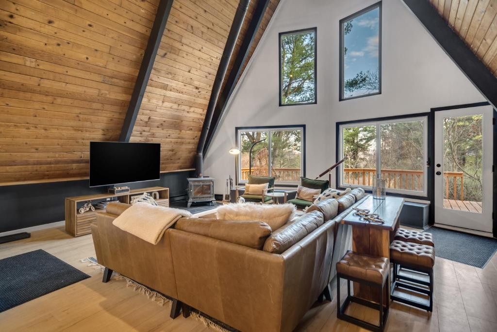 a living room with a couch and a tv at Camp Smores- Modern A-Frame with Pool in Newfield