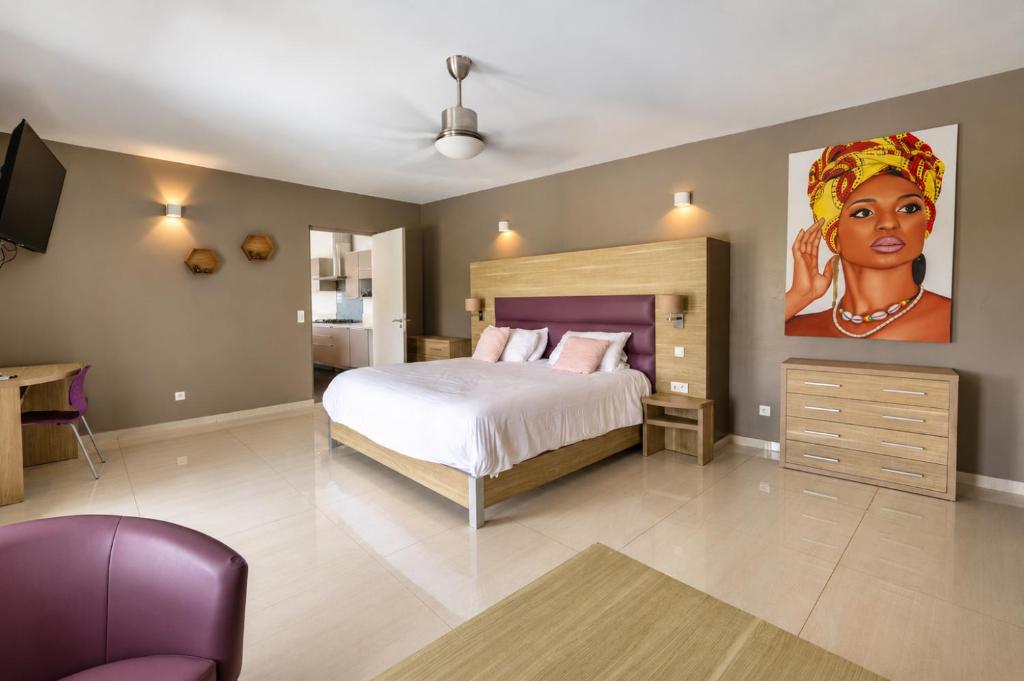 a bedroom with a bed and a painting of a woman at Villa Ellia - Terres Basses in Les Terres Basses