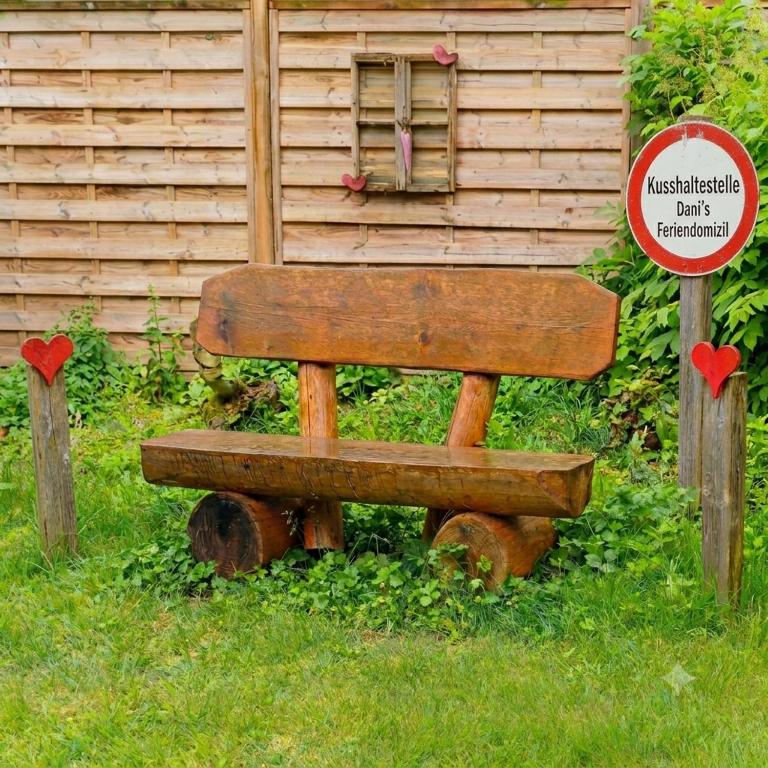 a wooden bench sitting in the grass next to a sign at Dani´s Feriendomizil in Wieda