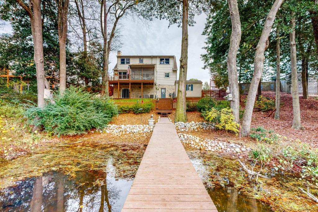 a house in the woods with a wooden walkway to the water at Salisbury Waterfront: Schumaker Pond Paradise! in Salisbury