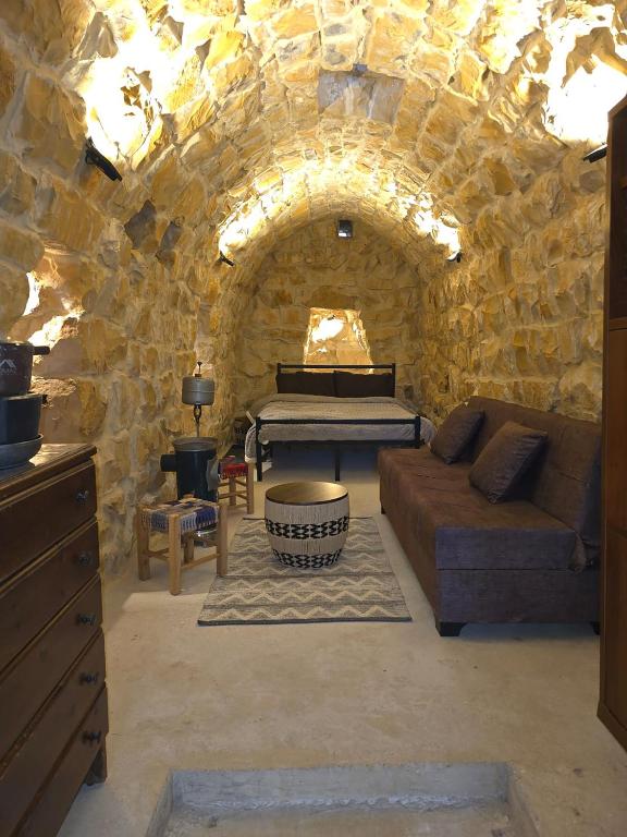 a stone room with a bed and a couch at Eagles Nest Guesthouse- Garden Lily House in Batroûn