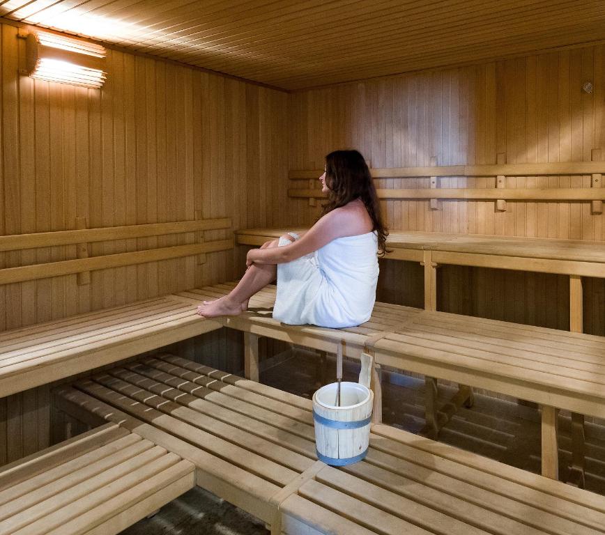 a woman is sitting in a sauna at Hotel Terme Marine Leopoldo II TERME & SPA in Marina di Grosseto