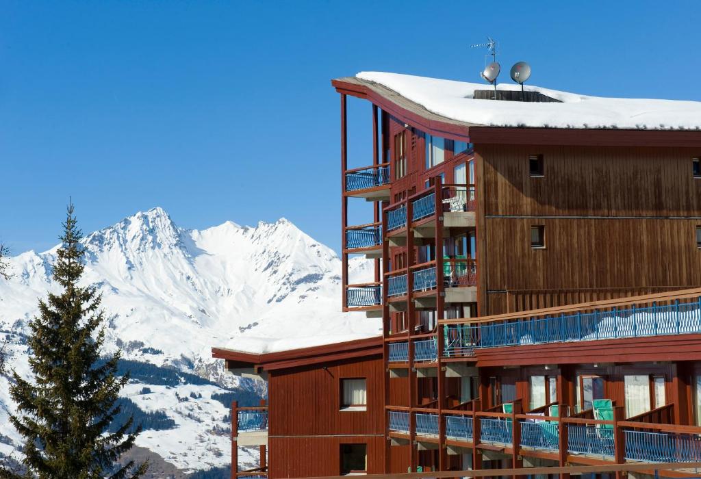 a hotel with snow covered mountains in the background at Résidences quartier Charmettoger - maeva Home in Arc 1800