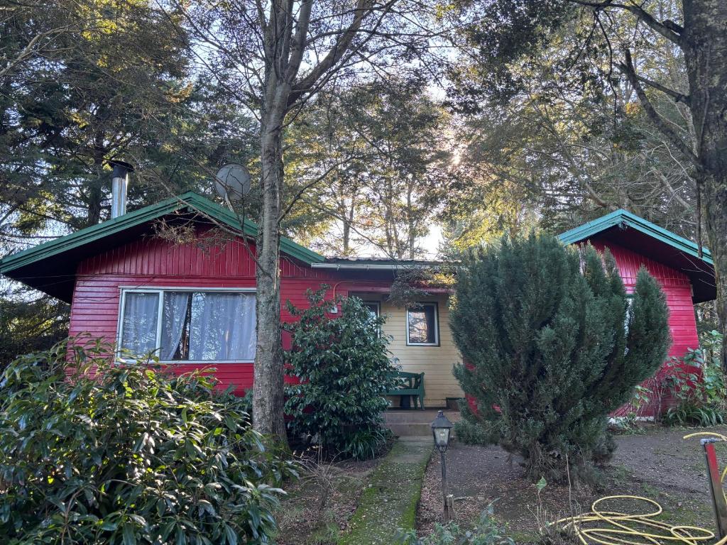 a red house with a tree in front of it at cabañas kiel in Llanquihue